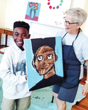 A young artist proudly shows off his work alongside local artist and volunteer Linda Blount. (Photos courtesy of Urban Hope)