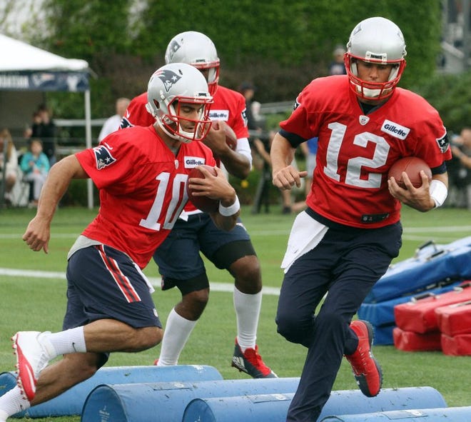 Tom Brady (12) and Jimmy Garoppolo go through drills during the first day of training camp on Thursday.