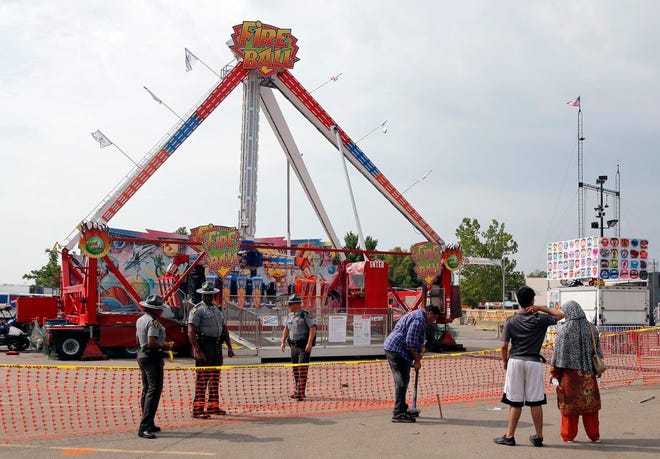 Passers by look at the fire ball ride as Ohio State Highway Patrol troopers stand guard at the Ohio State Fair Thursday,in Columbus, Ohio. [AP Photo/Jay LaPrete]