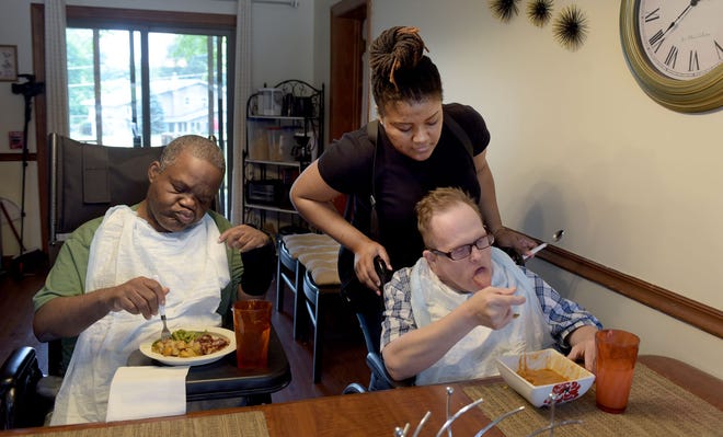 Yasmine Barionette helps Bob Trumbauer with his lunch. Sam Jamison, left, can usually eat without help. Both men live in an Upper Southampton, Pennsylvania, group home where Barionette works as a direct service professional, or DSP. It's run by KenCrest, a provider of services for adults with intellectual disabilities.