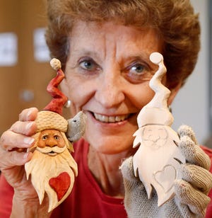 Myrna Keck shows a finished wooden Santa ornament and one that she is currently carving during the Edmond Senior Center's weekly woodcarving class. [PHOTO BY JIM BECKEL, THE OKLAHOMAN]