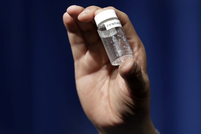 A reporter holds up an example of the amount of fentanyl that can be deadly after a news conference about deaths from fentanyl exposure at DEA Headquarters in Arlington, Va., in this June 6 file photo. [AP Photo/Jacquelyn Martin]