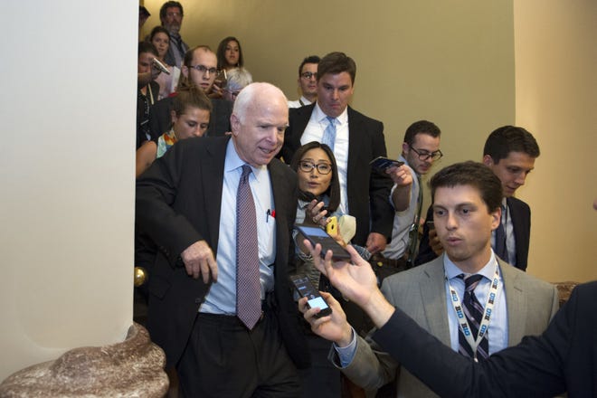 Sen. John McCain, R-Az., front left, is pursued by reporters after casting a "no" vote on a measure to repeal parts of former President Barack Obama's health-care law, on Capitol Hill in Washington on Friday. [AP Photo/Cliff Owen]