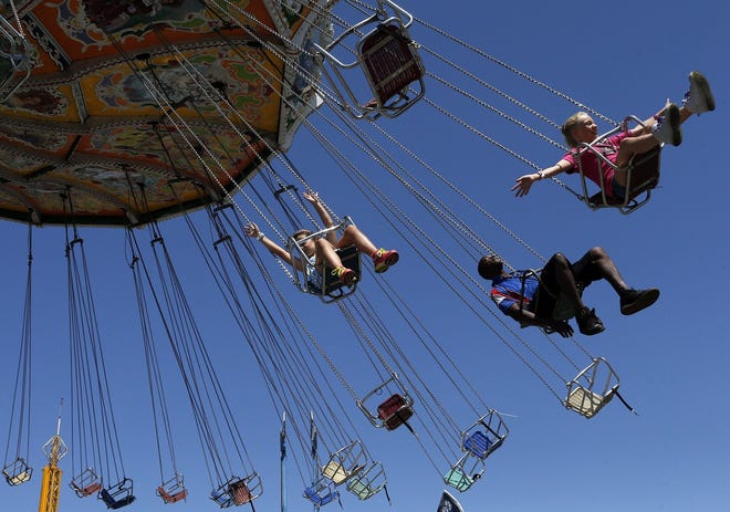 Torrea Bacelieri, 11, raises her arms while riding the "Wave Swinger" with Syddalee Schmidt, 8, and a fair employee during the first day of the rides reopening at The Ohio State Fair. [Brooke LaValley/Dispatch]
