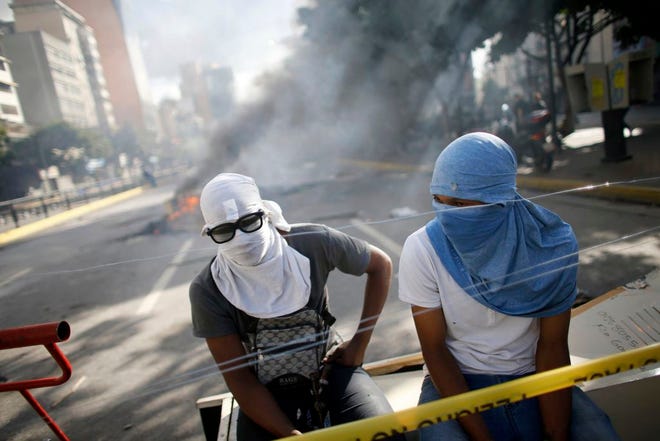 Anti-government demonstrators rest behind a barricade in Caracas, Venezuela, Sunday, July 30, 2017. Venezuelans appear to be abstaining in massive numbers in a show of silent protest against a vote to select a constitutional assembly giving the government virtually unlimited powers. Across the capital on Sunday, dozens of polling places were empty or had a few dozens or hundreds of people outside, orders of magnitude less than the turnout in recent elections. (AP Photo/Ariana Cubillos)