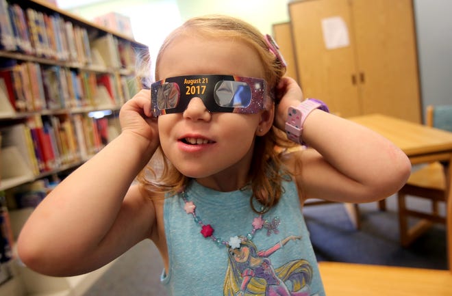 Emmalyn Johnson, 3, tries on her free pair of eclipse glasses Mauney Memorial Library in Kings Mountain on Wednesday. Glasses are being given away while supplies last. [Brittany Randolph/The Star]