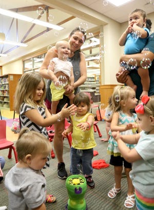 Children and their mothers chase bubbles Tuesday, Aug. 1, 2017, during an interactive activity at the Van Buren Library as part of the weekly Baby & Me Story Time. Every Tuesday at 10:30 a.m., Children's Librarian Yuvonka Tapp uses a variety of bouncing rhymes, finger plays, songs, music and books to entertain babies from birth to 3 years old. [JAMIE MITCHELL/TIMES RECORD]