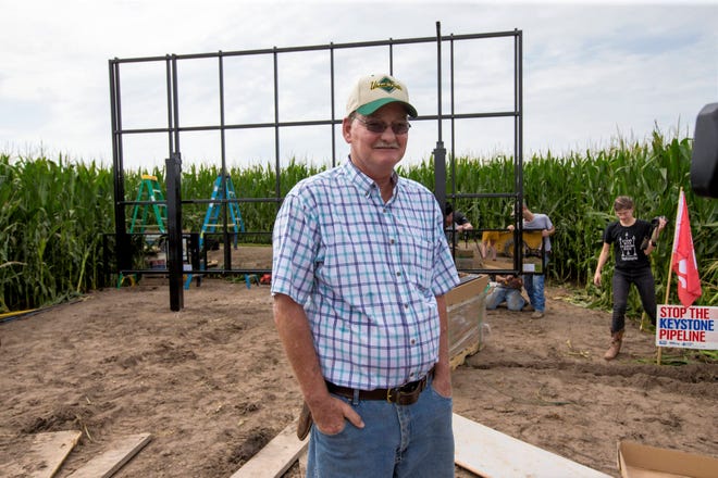 In this July 29, 2017 photo, corn farmer Jim Carlson of Silver Creek, Ne., waits to be interviewed by a television reporter while standing in front of solar panels he is building on his land in the proposed path of the Keystone XL pipeline. Despite new uncertainty over whether TransCanada, the builder of the Keystone XL pipeline will continue the project, longtime opponents in Nebraska aren’t letting their guard down and neither are law enforcement officials who may have to react to protests if it wins approval. (AP Photo/Nati Harnik)