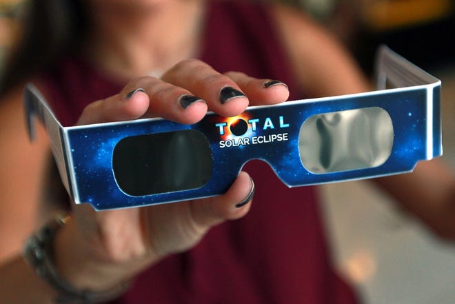 Morgan Huffman shows the eclipse glasses that are available for purchase at the Schiele Museum gift shop. [JOHN CLARK/THE GASTON GAZETTE]