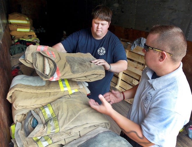 Volunteer fireman Robert Heussy, left, sorts through firefighter gear that is in storage at Carolina Warp Print in Gastonia, with fellow Union Road V.F.D. fireman Jake Bonnin. Heussy, through Fireman's Faith Ministry, has been collecting turnout gear, boots, fire hoses, cash, and other items to donate to under equiped fire departments in Nicaragua. [JOHN CLARK/THE GASTON GAZETTE]