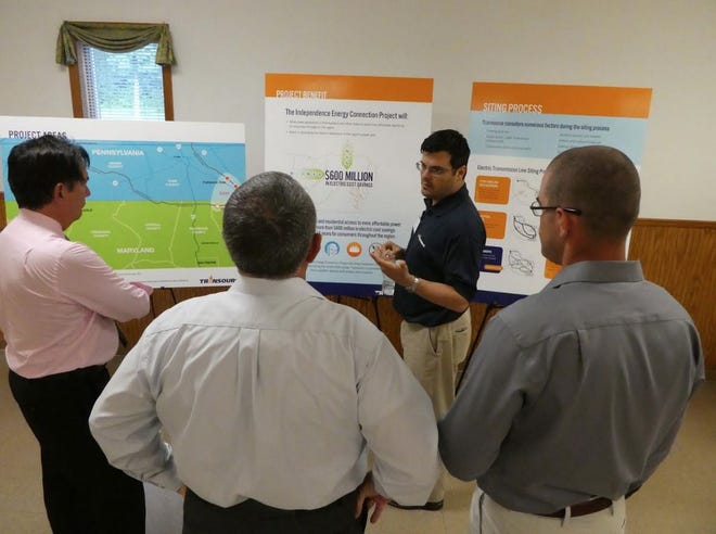 A representative from Transource reviews information about the Independence Energy Connection with attendees at a June open house in Franklin County.