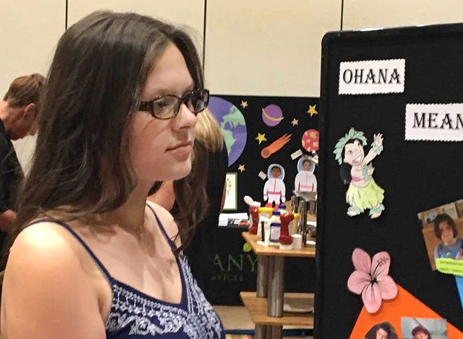 Olivia, 15, glances at a poster of other youngsters who are looking for a "forever home" like her. She spoke at a recent conference in the Poconos that focused on adoption.