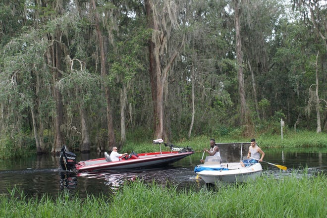 Leon Allen, left, and Eric Allen paddle their crippled power boat to shore as another boat passes them on the way to the boat ramp. [LINDA CHARLTON / CORRESPONDENT]