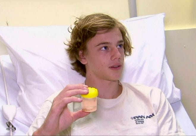 In this image made from video, Sam Kanizay, 16, holding a jar with creatures in it speaks from a bed of a hospital where he is treated, in Melbourne, Australia, Monday, Aug. 7, 2017. Kanizay walked out of the water with his feet and ankles covered in what looked like hundreds of little pin holes that were bleeding profusely. Kanizay’s father, Jarrod, said hospital staff had no idea what kind of creature could have caused the injuries. (Australia Pool via AP)
