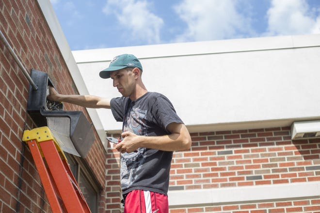 Eric Wieland of Cranberry fixes a security light outside of Lincoln High School on Friday in Ellwood City.
