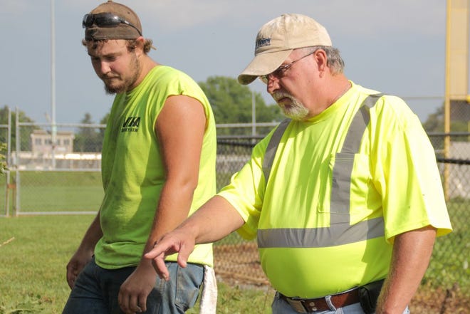 Denny Benshoff, Waynesboro maintenance superintendent, points out to truck driver Shade Smith, left, the plans for the walking trail as it progresses behind the Waynesboro Area Senior High School.