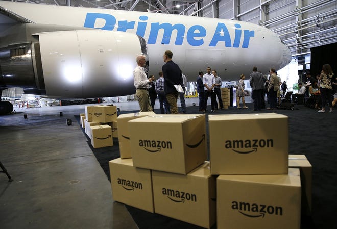 FILE - In this Aug. 4, 2016 file photo, Amazon.com boxes are shown stacked near a Boeing 767 Amazon "Prime Air" cargo plane on display in a Boeing hangar in Seattle. Buffeted by threats from Amazon drones and Uber to delivery by golf cart, the beleaguered U.S. Postal Service is counting on a different strategy to stay ahead in the increasingly competitive package business: more freedom to raise your letter prices. (AP Photo/Ted S. Warren, File)