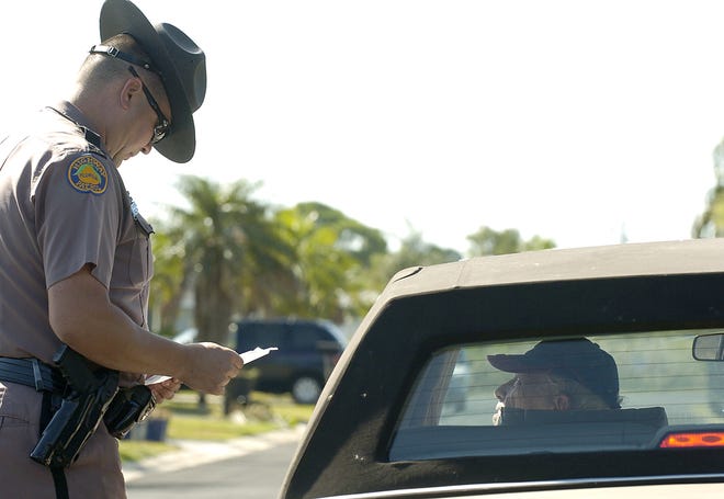 FHP Master Trooper Richard Moore hands eighty-two-year old Clement L. Grilliot a citation. Short about 200 troopers and seeking higher salaries to be more competitive with other law-enforcement agencies, the state Department of Highway Safety and Motor Vehicles is backing Gov. Rick Scott's call to boost pay as part of an election-year budget plan. [GATEHOUSE MEDIA FILE]