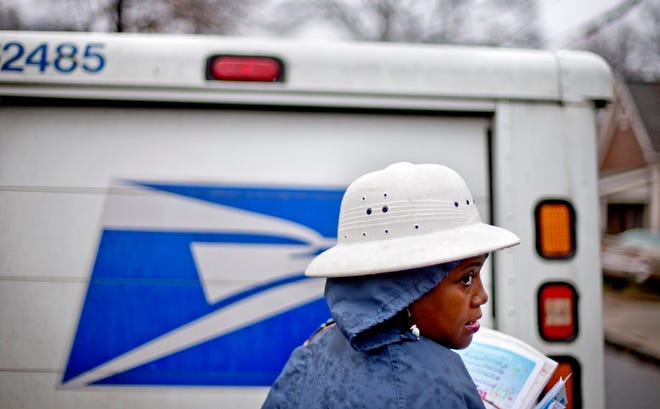 FILE - In this Feb. 7, 2014 file photo, U.S. Postal Service letter carrier Jamesa Euler delivers mail in the rain in Atlanta. Buffeted by threats from Amazon drones and Uber to delivery by golf cart, the beleaguered U.S. Postal Service is counting on a different strategy to stay ahead in the increasingly competitive package business: more freedom to raise your letter prices. (AP Photo/David Goldman)