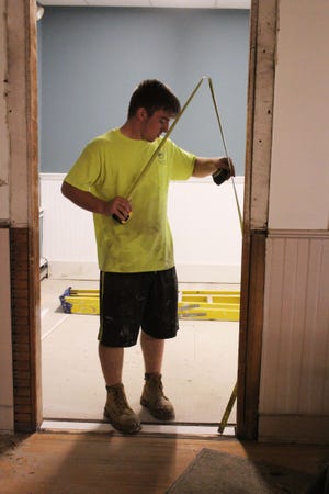 Tyler Camboia double-checks the rough opening of a door frame at the Parting Ways municipal building, being refurbished as part of a reorganization of town offices. The Town Clerk's office and records storage will take up much of the ground-floor space vacated by the police department when they moved to new quarters. [ROBERT BARBOZA/THE ADVOCATE/SCMG]