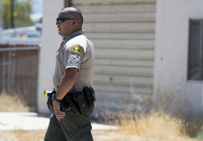 A San Bernardino County Sheriff's Department deputy walks in front of a garage where a marijuana grow was found following a fire in the backyard of a home in Victorville on Thursday. [James Quigg, Daily Press]
