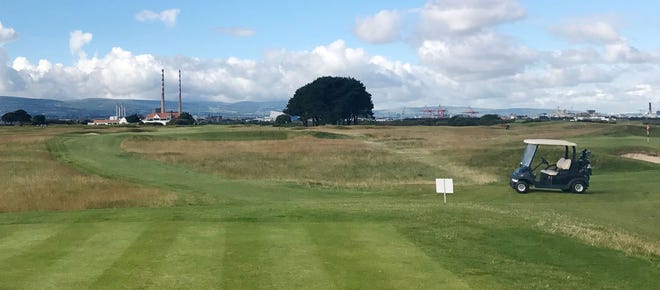 On the back nine of Royal Dublin Golf Club, golfers make their way back toward the clubhouse while taking in views of the Wicklow Mountains in the distance.