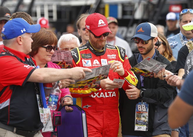 Dale Earnhardt Jr. signs autographs in the garage before practice on Saturday. Earnhardt has two wins at Michigan. [AP Photo/Paul Sancya]