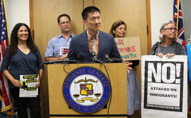 In this June 30, 2017, file photo, Hawaii Attorney General Douglas Chin speaks at a news conference about President Donald Donald Trump's travel ban in Honolulu. Hawaii's push to expand the list of relatives exempt from President Donald Trump's ban on travelers from six mostly Muslim countries is bogged down in court, where it has bounced from a federal judge to a federal appeals court and back to the same federal judge.