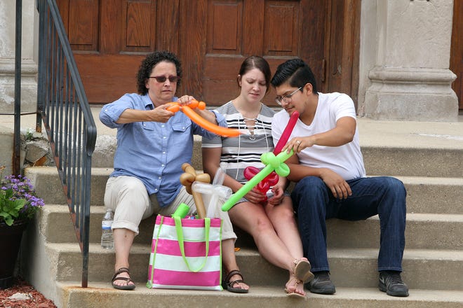 Trina Hingtgen (left) of Dubuque, Iowa, teaches Taylor Fleming (center) of Dubuque, Iowa, and Sergio Rubio of Dallas how to make balloon shapes to give out to the children during St. Mary Fest on Sunday, Aug. 13, 2017, at St. Mary's Church in Freeport. [JANE LETHLEAN/THE JOURNAL-STANDARD CORRESPONDENT]