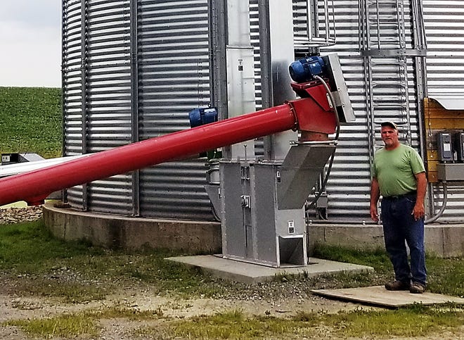 Phil Weaver of Bluegill Farms stands next to new grain transport and storage equipment that was largely funded through a state grant. [James Post/The Leader]