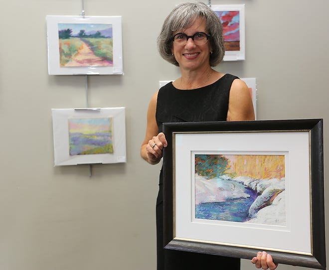 Artist Ginny Stocker, with some of her paintings at the Dover Public Library. (TimesReporter.com / Jim Cummings)