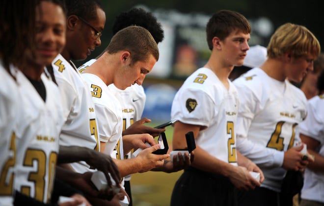 Shelby High School football players check out their American Legion World Series coins during their recognition before Game 12 of the series Monday. [Brittany Randolph/The Star]