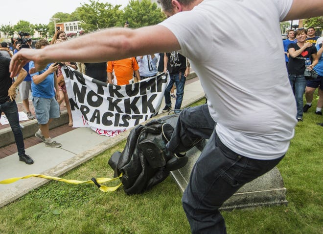 A protester kicks the toppled statue of a Confederate soldier after it was pulled down in Durham on Monday. The protest was in response to a white nationalist rally held in Charlottesville, Va., over the weekend. [Casey Toth/The Herald-Sun via AP]