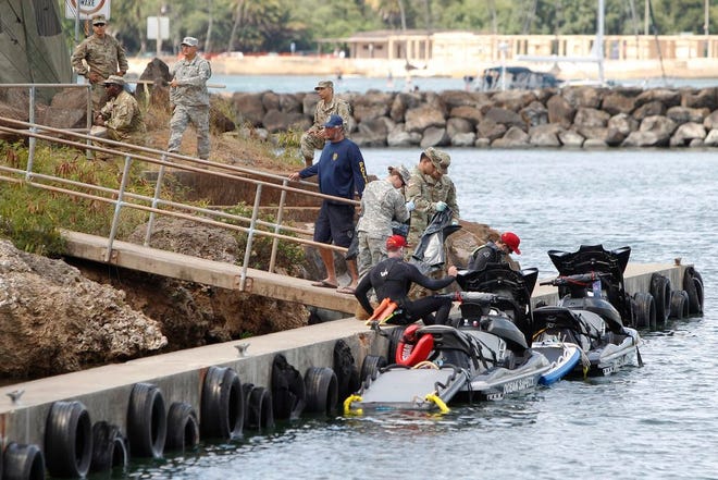 Honolulu ocean safety lifeguards on jet skis hand over materials to military personnel stationed at a command center at a boat harbor Wednesday in Haleiwa, Hawaii. An Army helicopter with five on board crashed several miles off Oahu's North Shore late Tuesday.