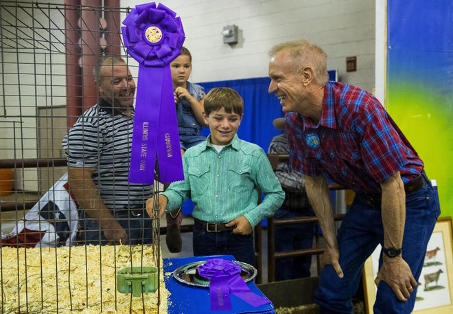 Illinois Gov. Bruce Rauner leans down to talk with Dex Gentes about his Grand Champion Rabbit Market Pen before it's auctioned off at the 2017 Governor's Sale of Champions at the Illinois State Fair Tuesday, Aug. 15, 2017. Gentes dad Chris and sister Sloan are at left. [Ted Schurter/The State Journal-Register]
