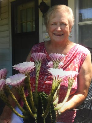 Pat Myrick stands outside her North Topeka home with her Easter lily cactus that produced 10 blooms on a single day in July. (Submitted)