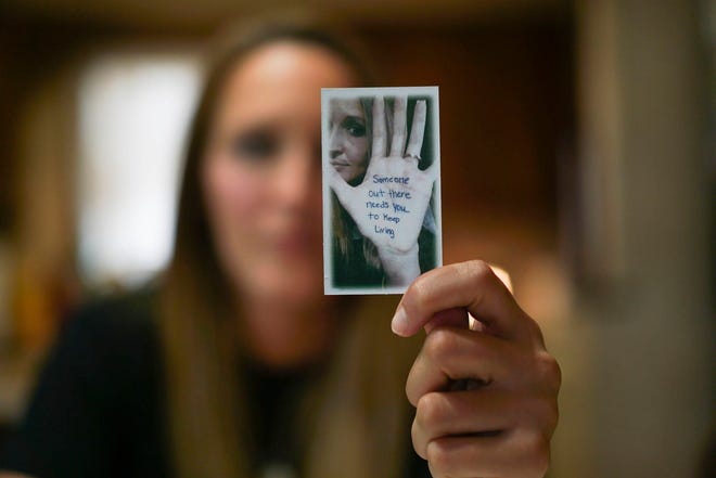 In this Aug. 9, 2017, photo, Koriann Evans, a former drug addict, holds up a photo of herself with an anti-addiction message written on her hand at her home in Bellevue, Ohio. Evans was hooked on heroin for over a decade until she overdosed while driving her car with her two children in the back, after which she stopped using drugs and started speaking about her former addiction. Police and rescue crews say drivers overdosing on heroin and other drugs are driving up the number of car crashes. (AP Photo/Dake Kang)