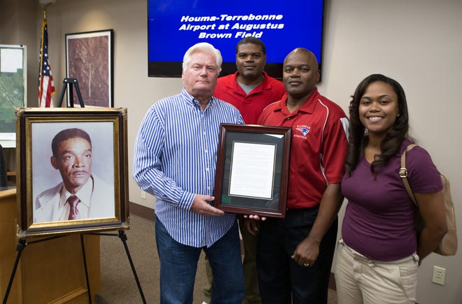 Houma-Terrebonne Airport Commission Chairman Mike Kreller (from left) presents a plaque to Eric Brown, Gus Brown and Natalie Brown-Williams at a ceremony renaming the airport in honor of their grandfather Augustus Brown.[Chris Heller/Staff -- houmatoday/dailycomet]