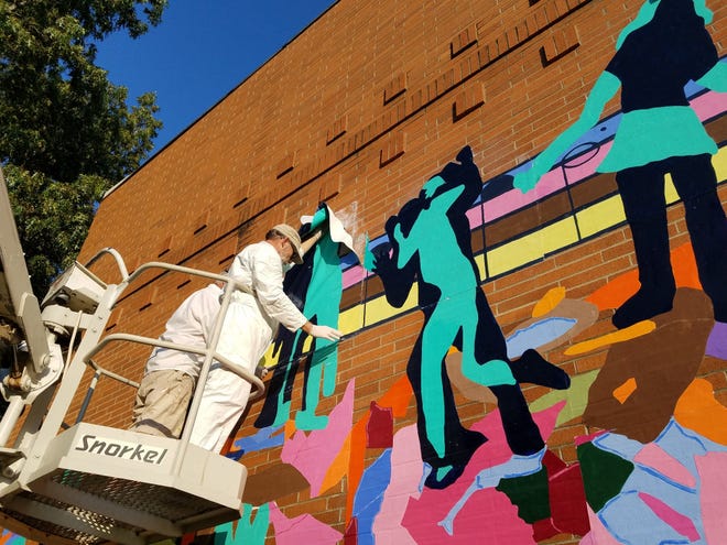 Erie artists Tom Ferraro, at left, and Ed Grout apply panels of a mural to the exterior of the Martin Luther King Center in Erie on Tuesday. The 45-foot by 20-foot mural is called "Let the Children Sing" and was created with the help of children who take part in after-school and summer programs at the center, which is located at 312 Chestnut St. The mural is on the north side of the building, facing West Third Street. [PAT BYWATER/ERIE TIMES-NEWS]