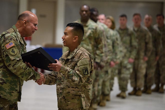 Maj. Gen. Kenneth Jones hands a flag box to Spc. Chester Calica during a Warrior Citizen ceremony on Thursday at Fort Bragg. The U.S. Army Reserve soldiers recently returned from a deployment with the 18th Airborne Corps. [Andrew Craft/The Fayetteville Observer]