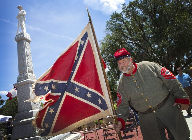 Randy Kerlin, Florida Society commander of the Military Order of the Stars & Bars, picks up the Confederate battle flag for the start of the rededication of Marion County's Confederate memorial monument at the Ocala-Marion County Veterans Memorial Park in 2011. The local branch of the NAACP wants the statue removed from public land. [Doug Engle/Staff photographer/File]