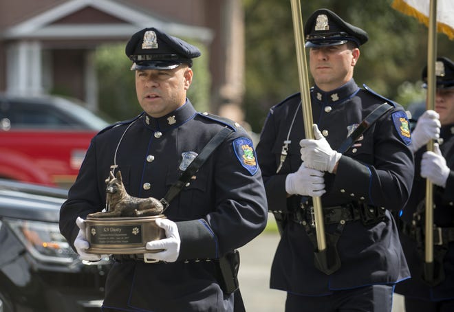 Arlington Police Sgt. Bryan Gallagher carries the ashes of Dasty during the memorial for the Arlington Police K-9 at the Arlington Police Department, Aug. 17, 2017. Dasty died on June 18, after working in Arlington for nearly 11 years. [Wicked Local Staff Photo/John Walker]