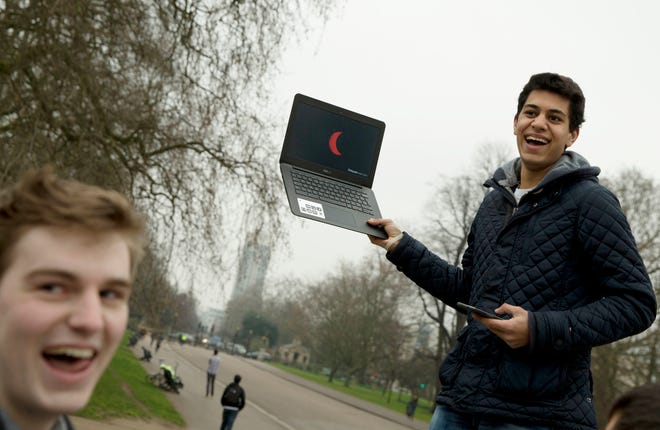 FILE - In this Friday, March, 20, 2015 file photo, a student holds up a laptop computer with a live television feed showing the progress of total solar eclipse to a group of his friends, near the Albert Memorial in London. For the 2017 eclipse in the United States, NASA and other news and television outlets will offer live coverage of the celestial event. (AP Photo/Alastair Grant)