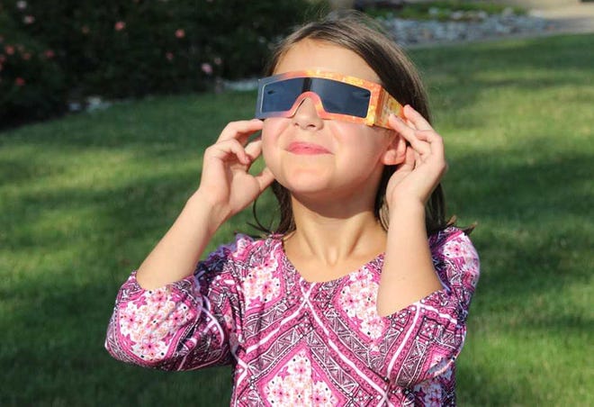 Emerson Smith, 7, of Upper Dublin, tries on a pair of sunglasses designed to protect her eyes during a solar eclipse. Folks who want to look at the solar eclipse on Aug. 21 should wear glasses certified by the International Organization for Standardization, according to NASA.