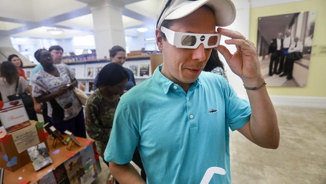 Dave D’Addario of West Palm Beach tries on a free pair of solar eclipse glasses at Mandel Public Library in West Palm Beach Tuesday, August 15, 2017. (Bruce R. Bennett / The Palm Beach Post)