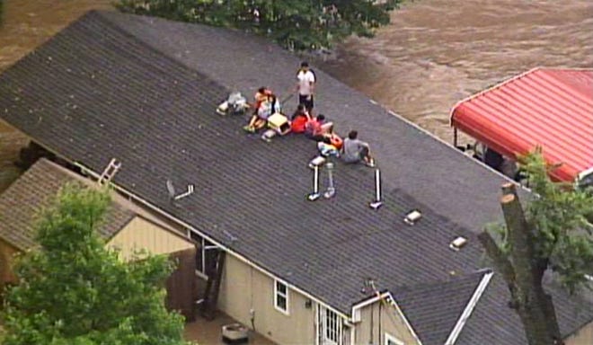 This aerial photo from a video by KCTV5 shows a family forced onto the roof of a home in Overland Park, Kan., on Tuesday, Aug. 22, 2017, after heavy rains caused flash flooding in the Kansas City area. Flash flood warnings have been issued across the area. (KCTV5 via AP)