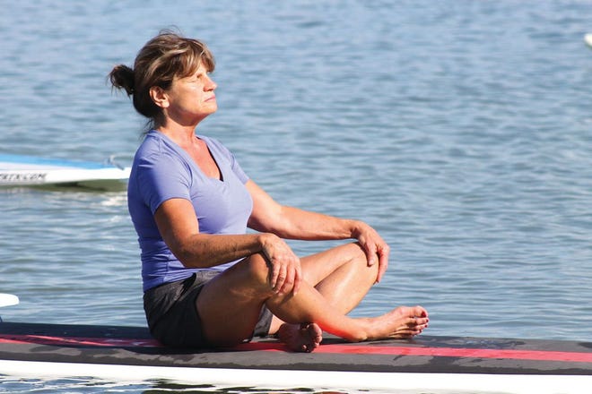 Patty Davidson enjoys the sun and waves 
while doing a simple seated pose 
during a YogaCore class at Fishers Lake.