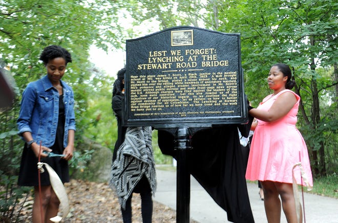 Members of the 2015-16 Association of Black Graduate and Professional Students Yoanna McDowell, left, and Tiffanesha Williams, unveil the memorial to James T. Scott, a black janitor that was lynched from the Steward Road Bridge in 1923, in September 2016. Scott was a married at the time and working as a janitor at the MU medical school when he was accused on April 20, 1923, of raping the 14-year-old white daughter of an MU German professor, Hermann Almstedt. No members of the lynch mob were convicted of a crime. [DON SHRUBSHELL/TRIBUNE]