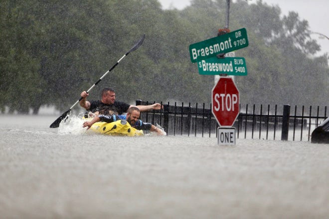 Two kayakers try to beat the current pushing them down an overflowing Brays Bayou along S. Braeswood in Houston, Texas, Sunday, Aug. 27, 2017. Rescuers answered hundreds of calls for help Sunday as floodwaters from the remnants of Hurricane Harvey climbed high enough to begin filling second-story homes, and authorities urged stranded families to seek refuge on their rooftops. (Mark Mulligan/Houston Chronicle via AP)