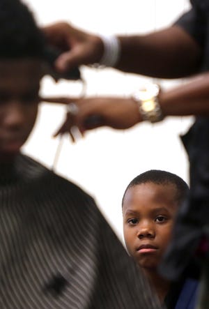 Khamani Jones, 12, waits in line to get haircut at Holly Oak Park in Shelby during the Camp Coach Rhodes 7th Annual Free Back-to-School Haircuts event on Saturday. [Brittany Randolph/The Star]